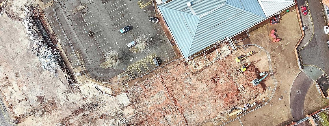 demolition site on shopping centre site, interior of building exposed by works. drone shot from above
