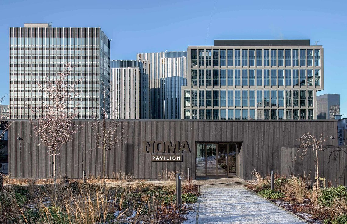 wooden clad pavilion with glass buildings
