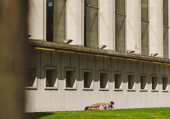 Case Study Photography Cover For Urban Lifestyle And Local Area Photography - Spinningfields, Manchester, showing an architectural shot of a building with a man lying in the sunshine in front