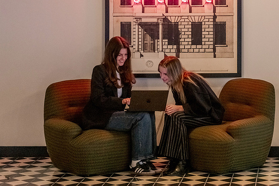 Commercial lifestyle photography team collaboration London office, workers sit under neon sign in trendy office space
