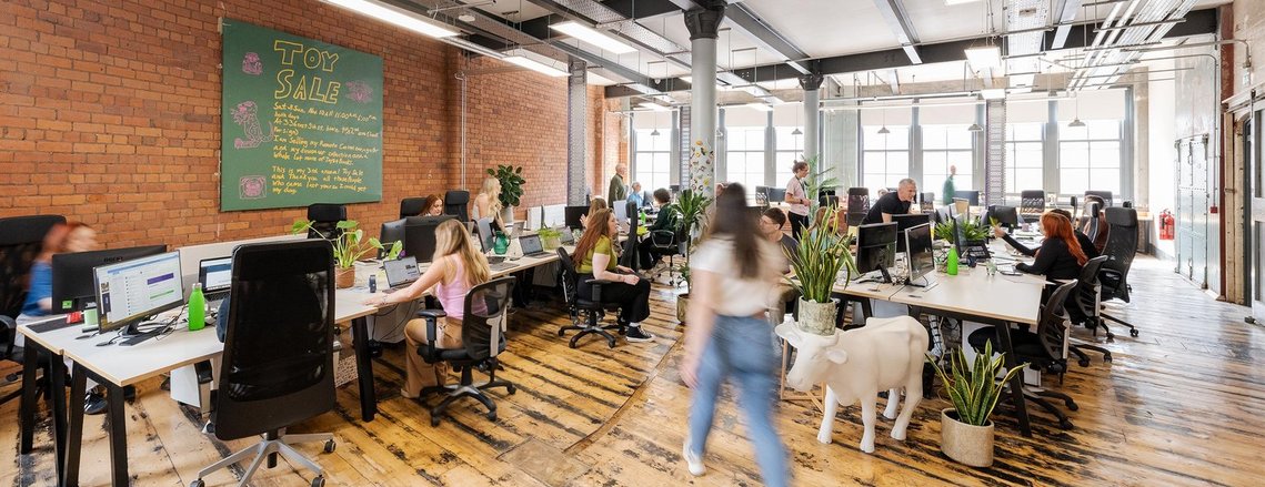 commercial lifestyle photography wide angle shot of open-plan studio, team members sitting at desks or moving around space