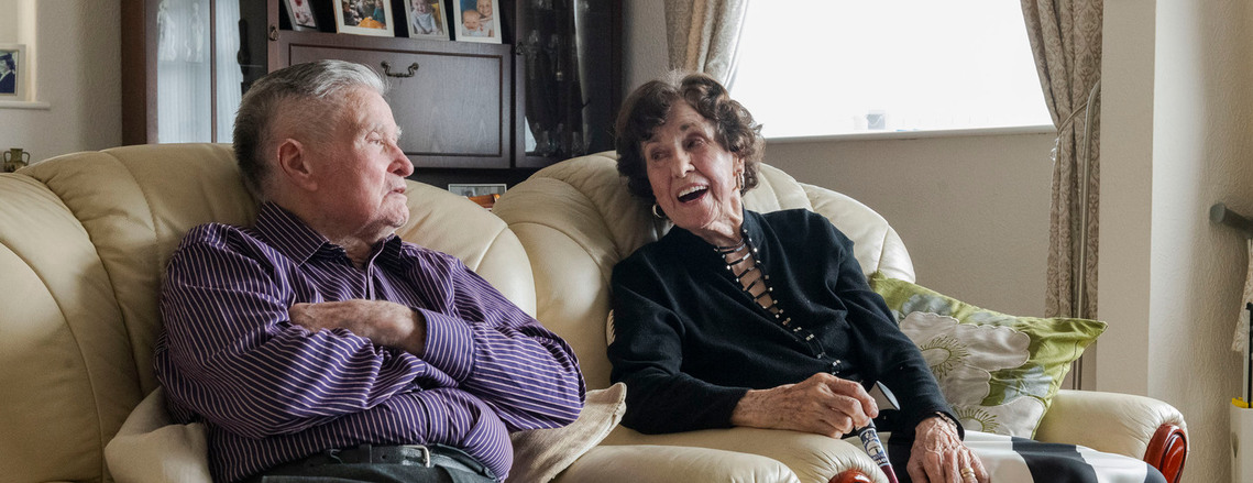 elderly couple sitting in armchairs reminiscing
