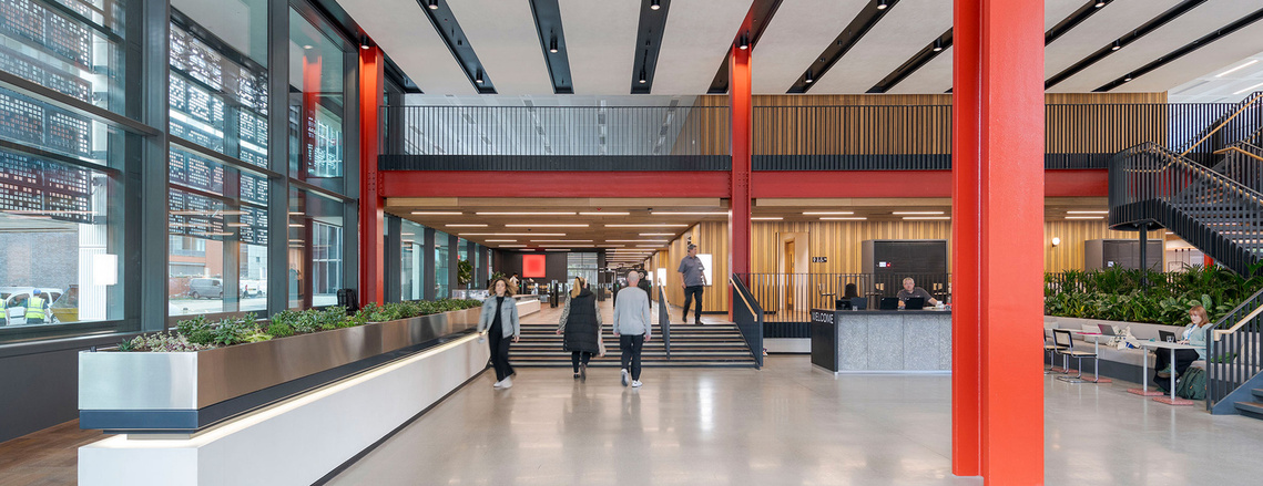 architecture and interior photography of vast interior reception space in modern building with people walking through the frame