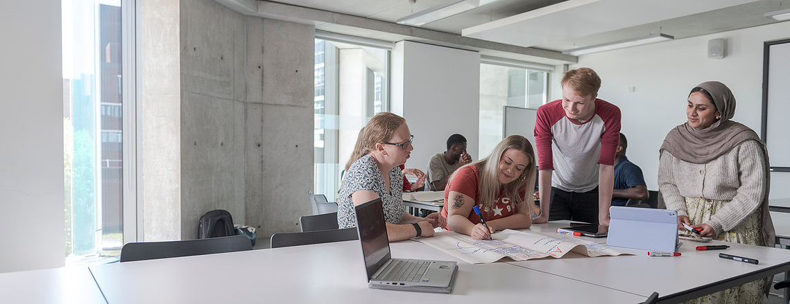 group of students gathered around a desk working on a project