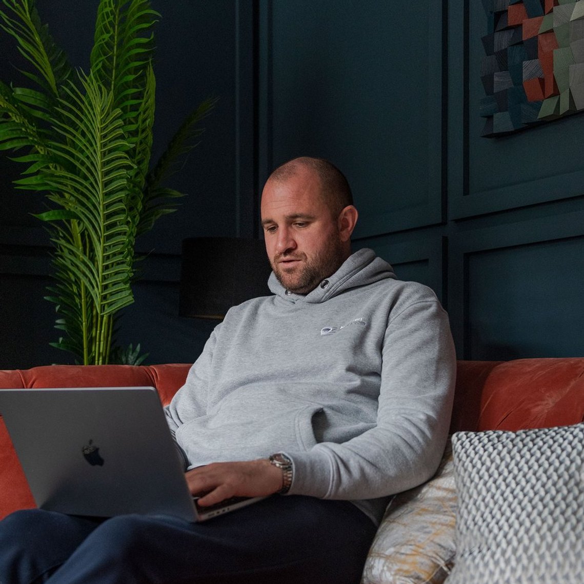 person working from home, sat in living room environment with laptop on knew