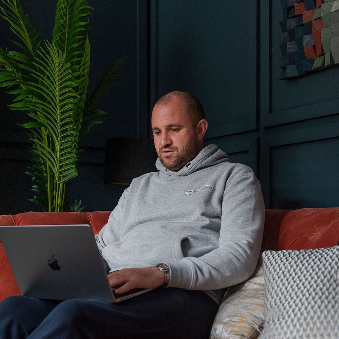 person working from home, sat in living room environment with laptop on knew