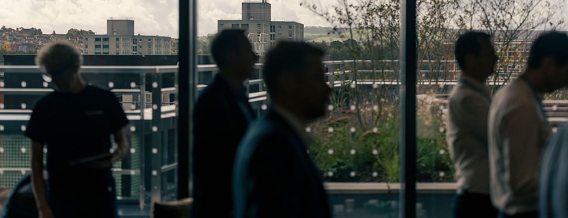 people in silhouette against a view out over brostol