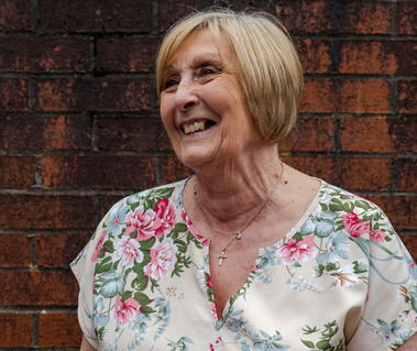 portrait of woman stood against red brick wall