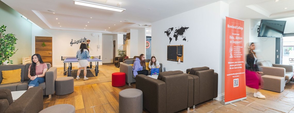 Wide shot of a student breakout space with people playing broad games and table tennis and moving around.
