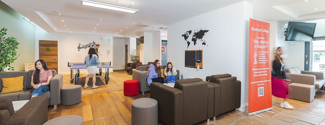 Wide shot of a student breakout space with people playing broad games and table tennis and moving around.