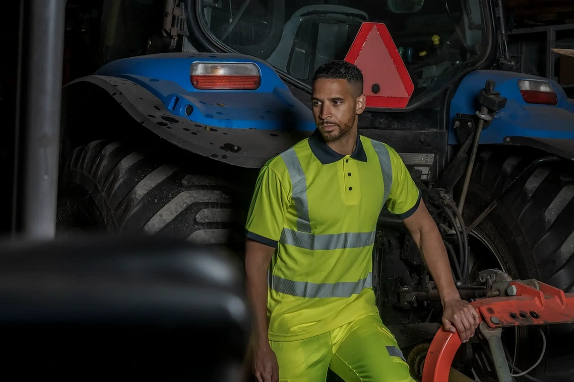 Creative direction and production photography for Rodo Ltd, model in hi-vis wear posed next to tractor 