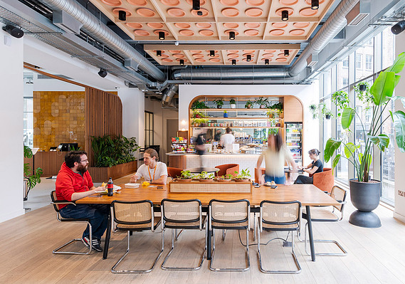 Clockwise photography case study cover showing a shared space in a workplace building, tables and chairs and plants with workers
