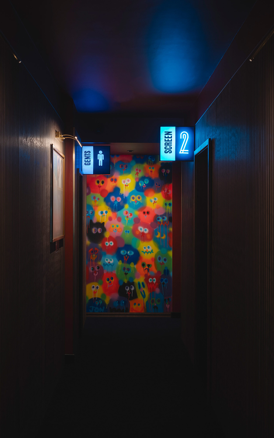 architectural photography showing corridor in cinema with screen signs and colourful mural on wall