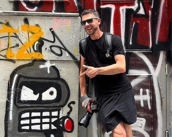 Contact page image of commercial photographer Steve Longbottom, shown in city scene with camera and graffiti 