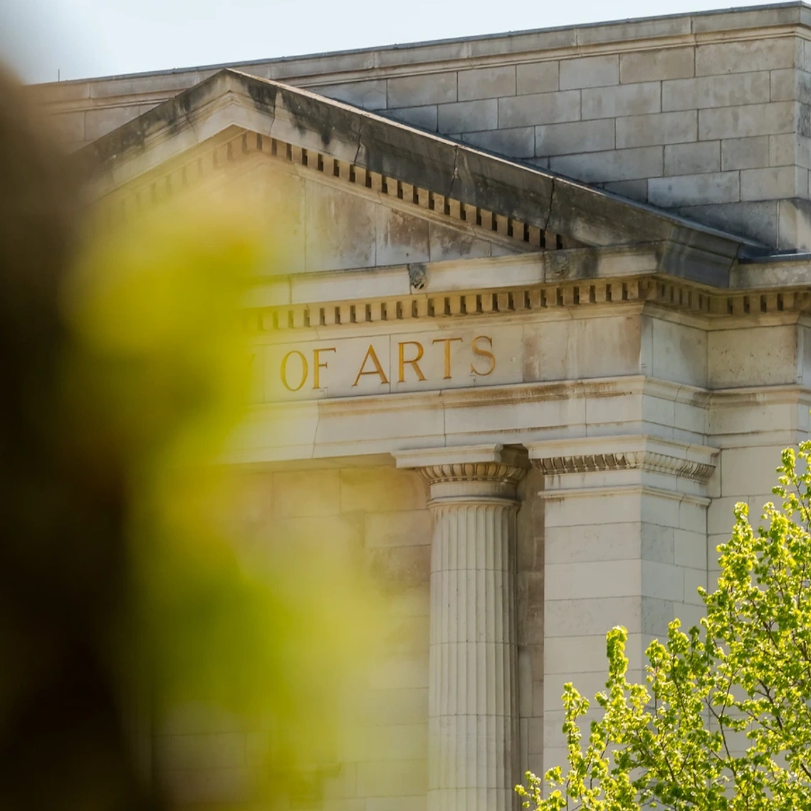 View of heritage building with columns and greenery in foreground
