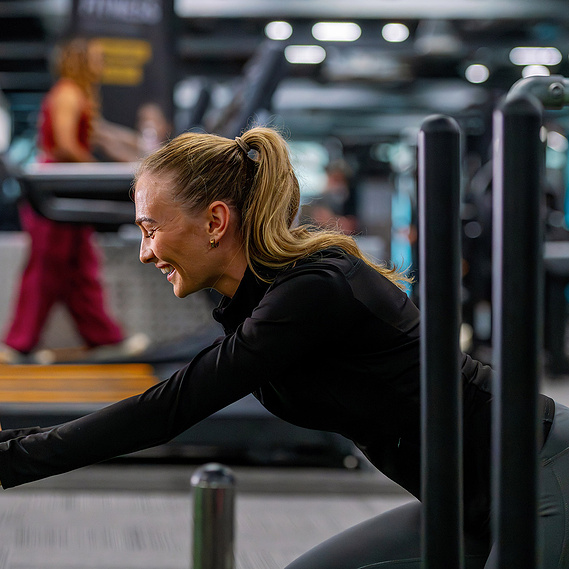 PureGym facility inside 3 Hardman Street building photographed during lifestyle shoot. Woman doing resistance exercise
