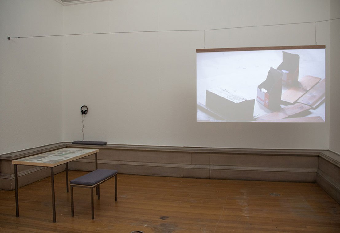 A beige room with a hanging projection screen and wooden table