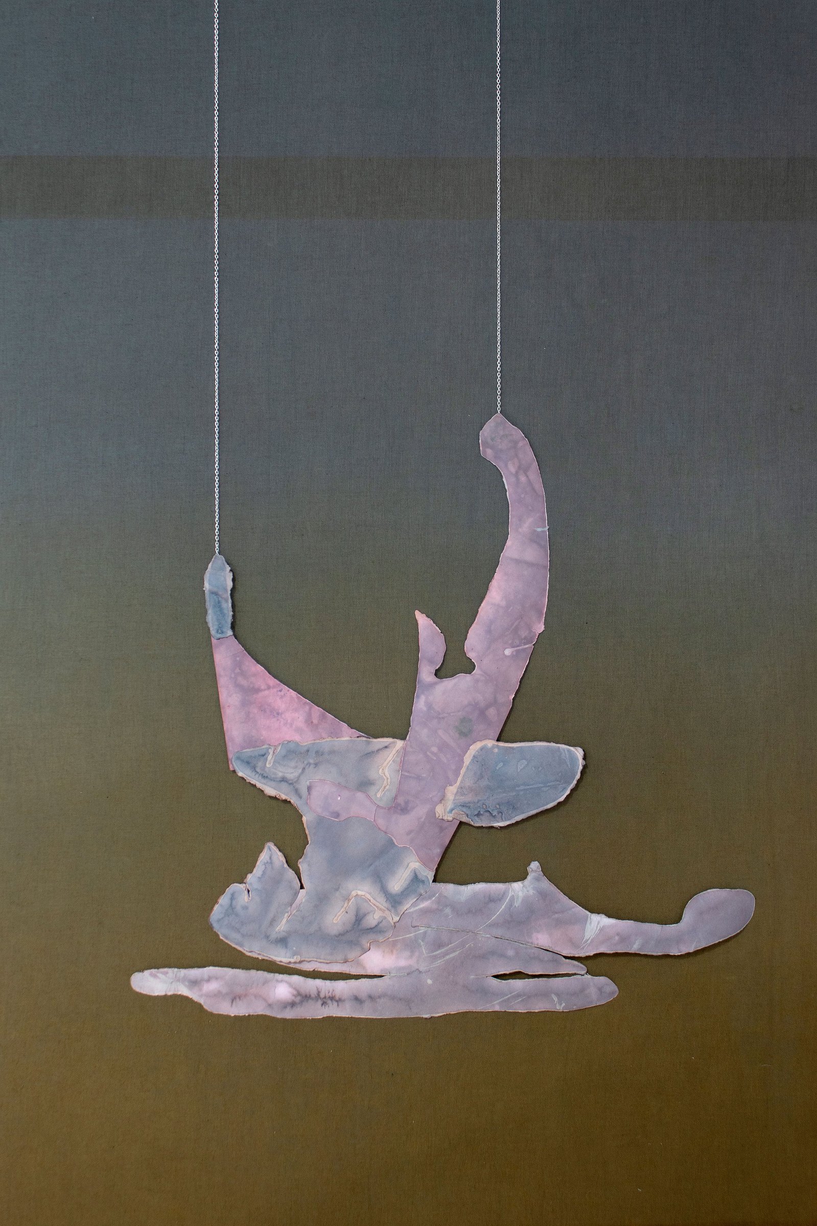 Jumping or sitting figure made from paper object on green fabric background. Jamie Kane