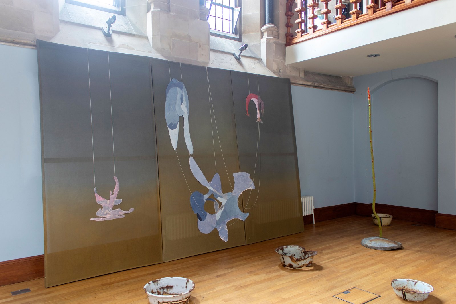 Painting canvas with paper objects and green fabric in a blue room. Jamie Kane