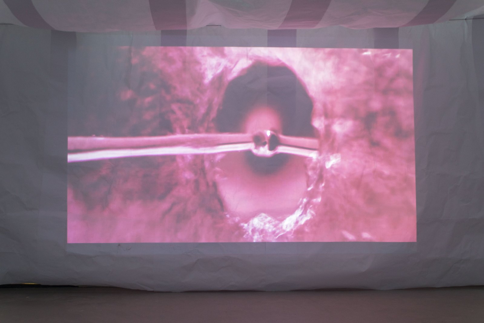 Projection onto paper showing a purple tinted image of water pouring onto a mirror, rotated 90 degrees. Jamie Kane
