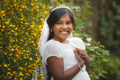 first Holy Communion portrait of a young girl in a white dress, taken in natural light. Captured in London, this elegant image highlights the joy and grace of this special Catholic milestone. Holy Communion photographer serving London and West Essex