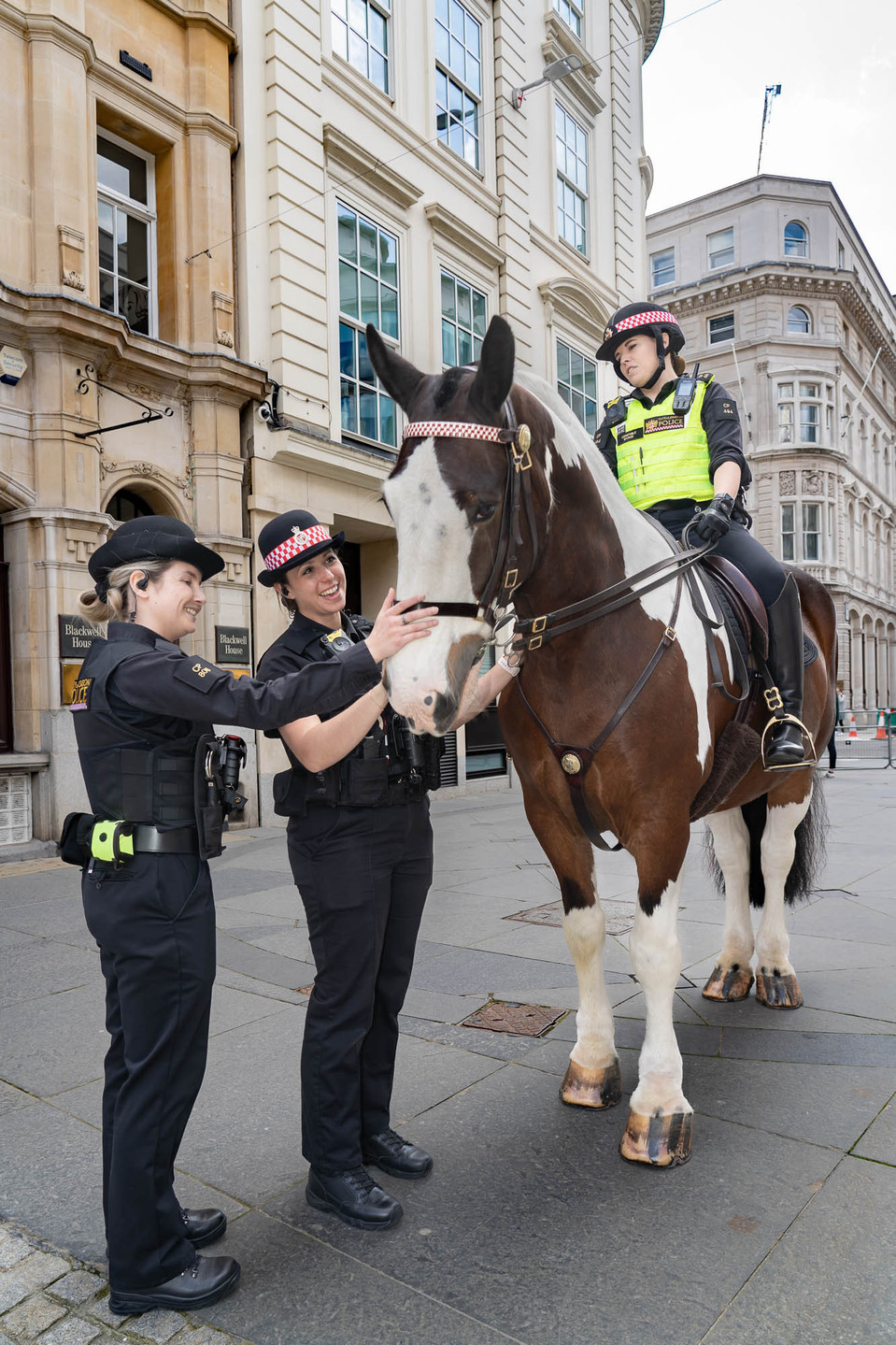 Female City of London Police officers pet a police horse