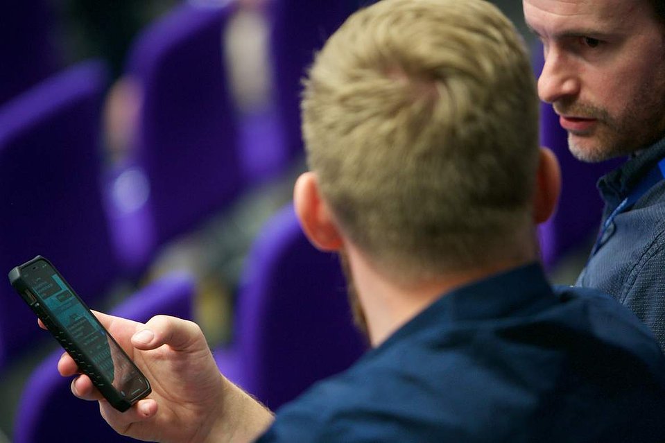 Close up colleagues discuss a mobile message at a London event