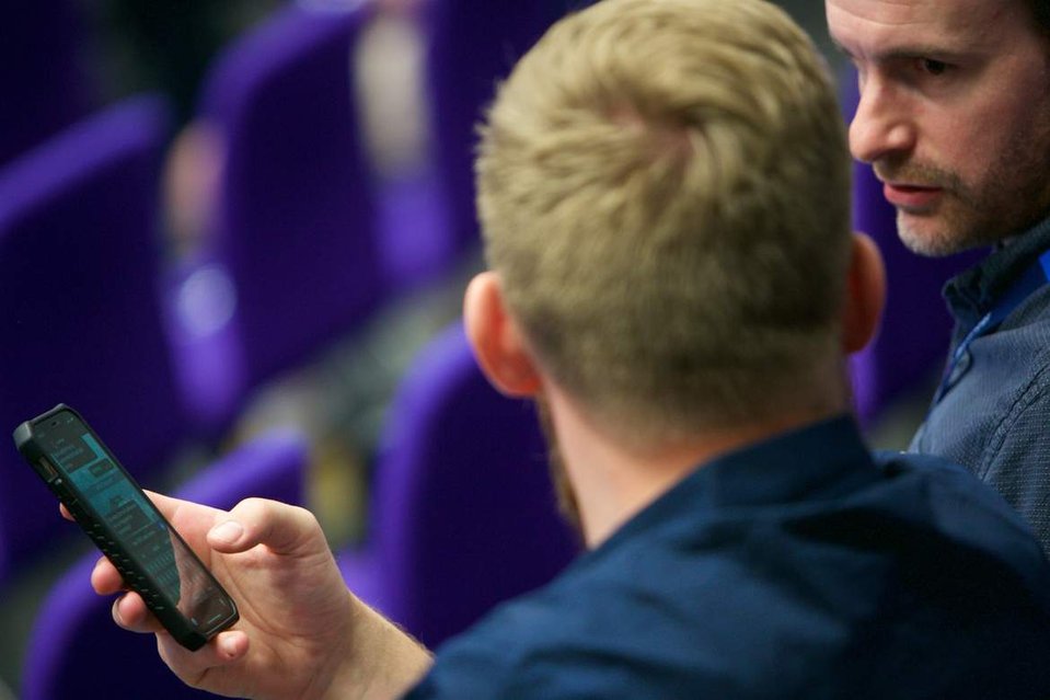 Close up colleagues discuss a mobile message at a London event