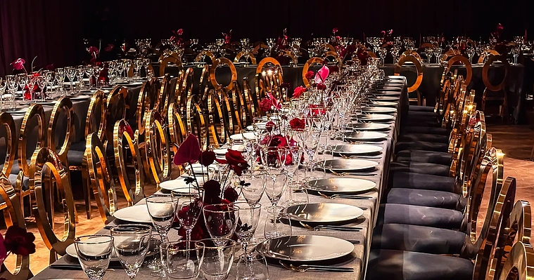 A corporate dinner event with long tables set with placings and table centres