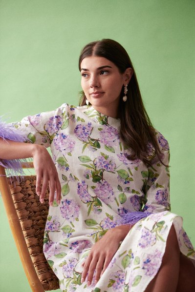 Brunette model wearing a floral print dress on green background
