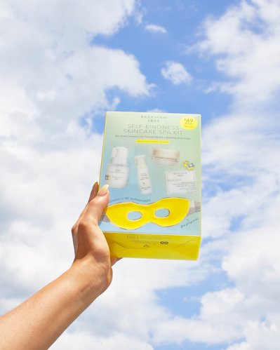 Hand holding skincare set to the blue sky with clouds
