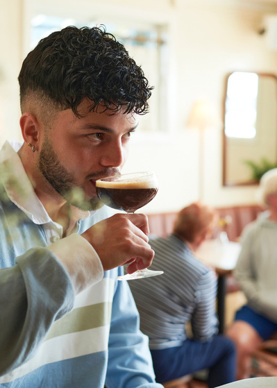 man drinking espresso martini cocktail in restaurant
