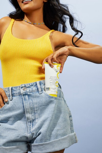 Indian model in yellow swimsuit with denim shorts and sunscreen product in pocket
