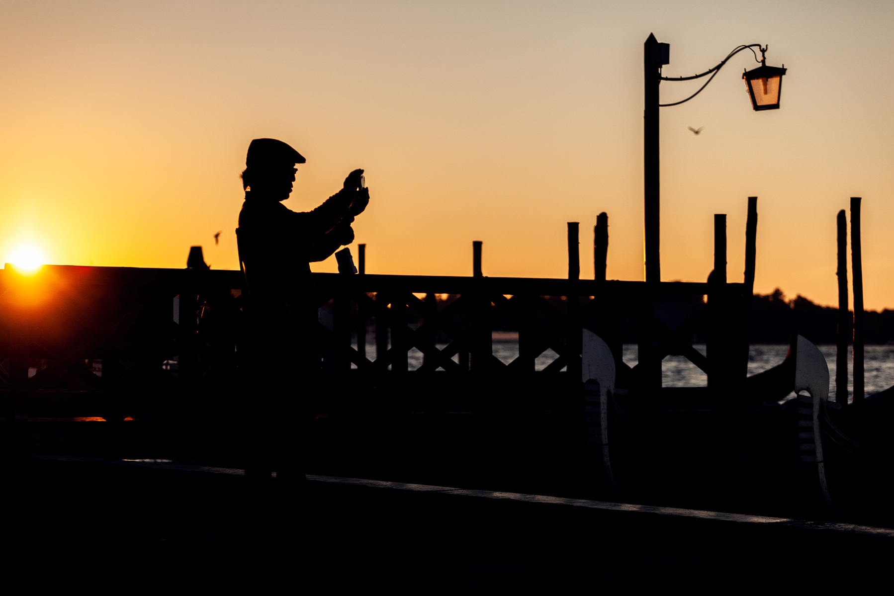 A man takes a photo during sunset in Venice, Italy.