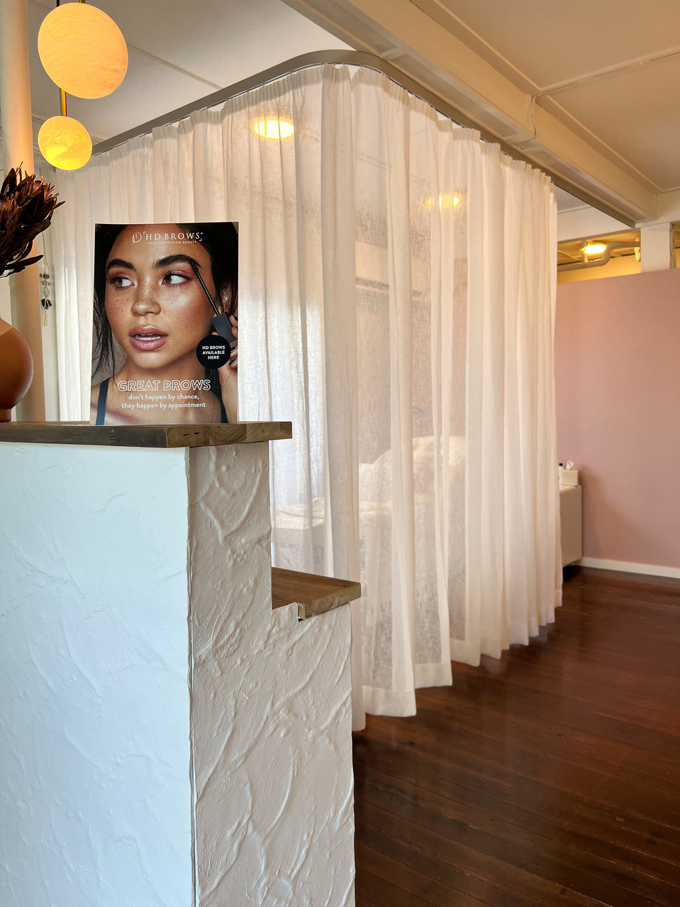 Studio interior picturing white curtain, white textured reception desk and small and large alabaster globe lights.