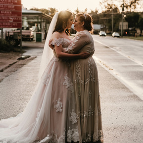 Brides embracing and kissing on a rain soaked road in Dayboro, Qld after an afternoon sunshower on their wedding.