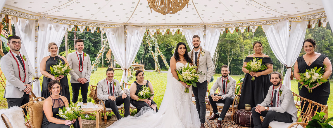 Bride and groom with bridal party members under ornate moroccan style, open-air tent for wedding in Maleny. 