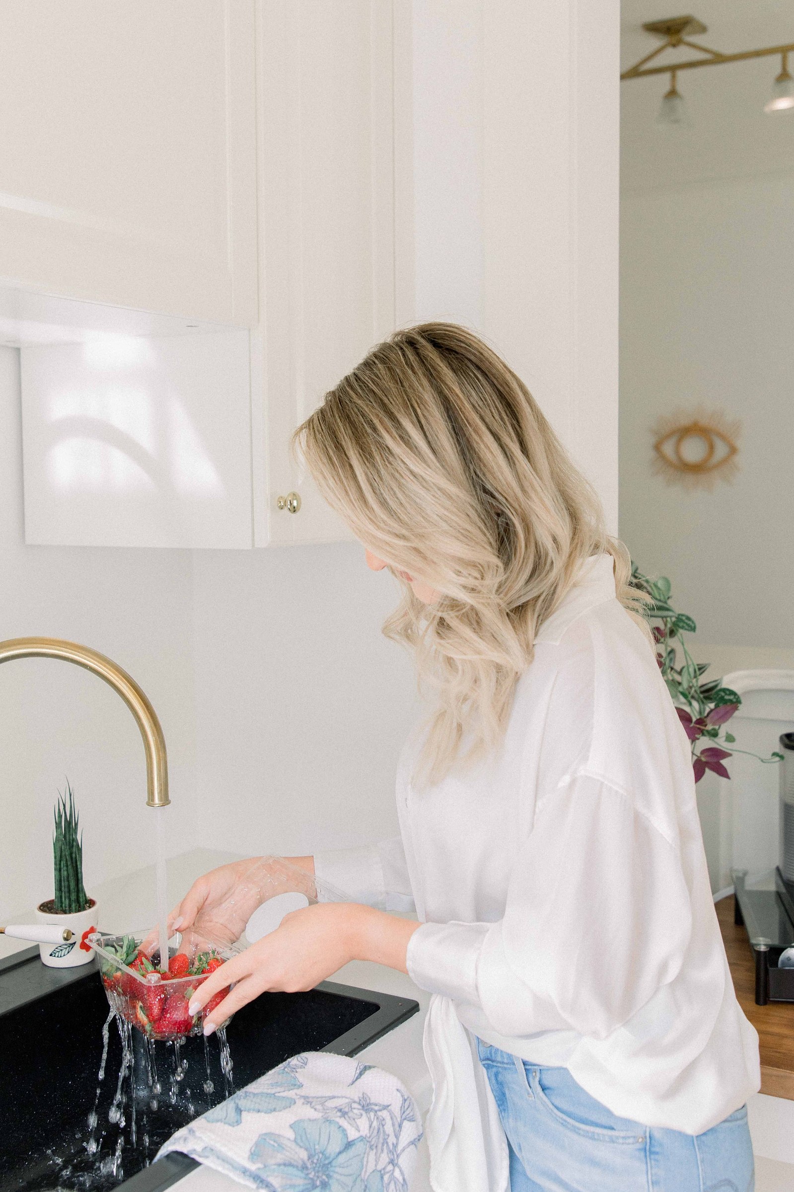 Portrait of a woman washing strawberries in a studio kitchen. Light and airy photography. Emily VanderBeek Photography. Niagara Photographer, Ottawa Photographer, Montreal Photographer.
