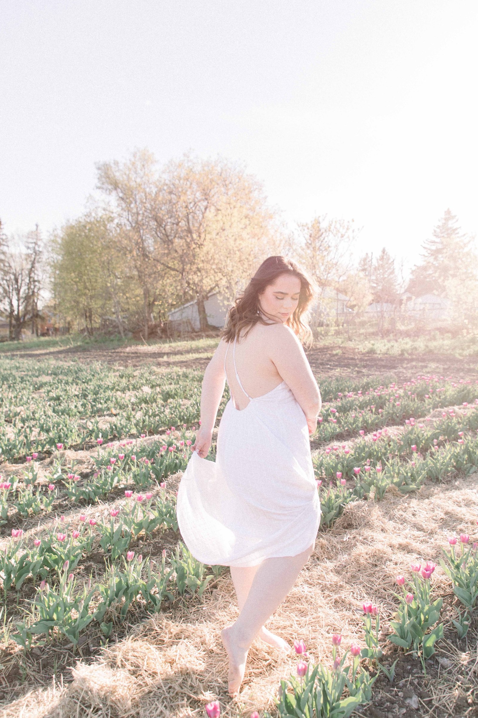 Portrait of a woman in a white dress dancing & twirling around in a tulip field. Vankleek Hill Portrait Photographer, L'Orignal, Champlain, Prescott-Russell, Family Photography, Candid Photography, Emily VanderBeek Photography.