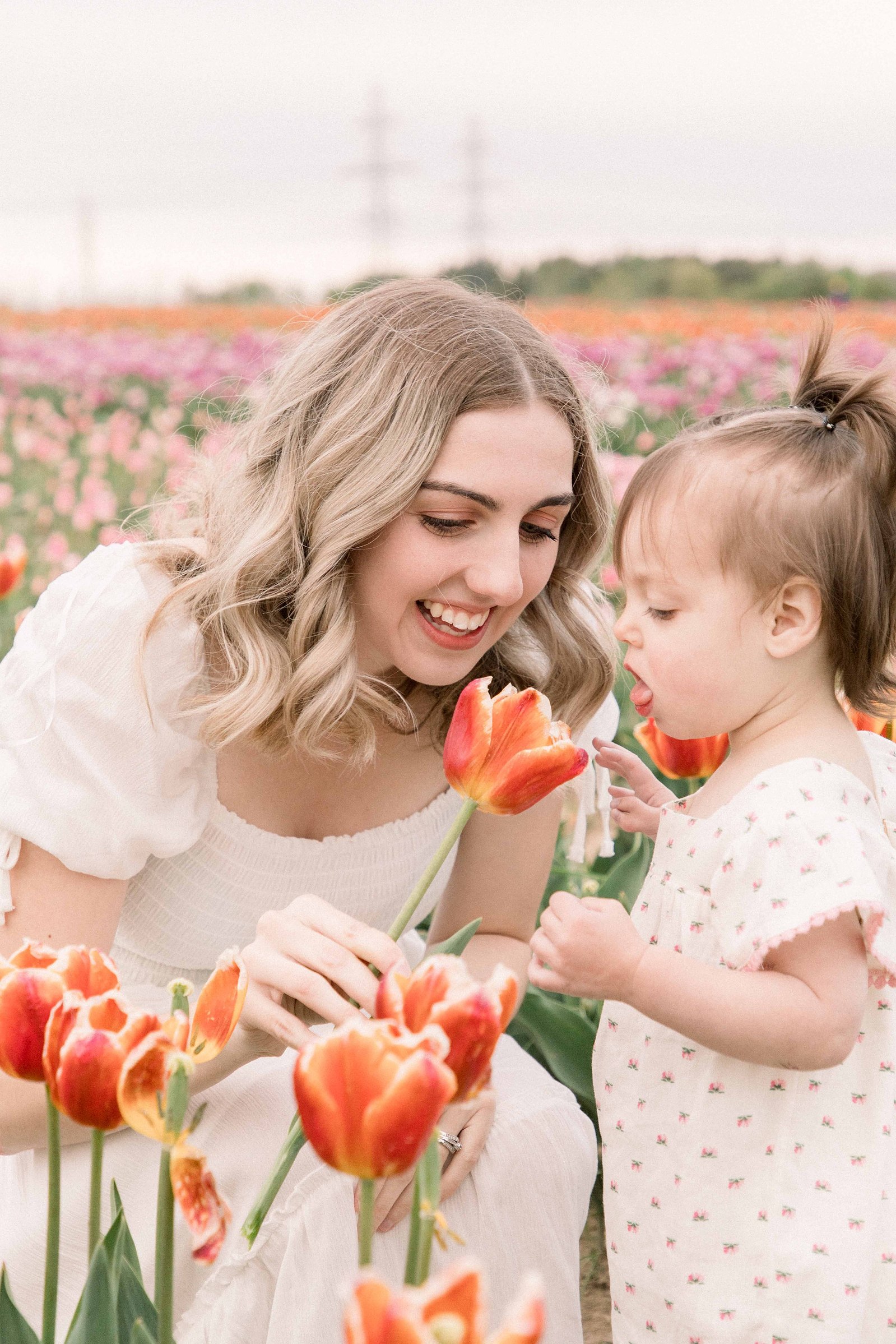 Portrait of mother and daughter at a tulip farm in Niagara, smelling the flowers. Niagara portrait photographer. Niagara family photographer. Niagara photographer. Emily VanderBeek Photography. Candid photography. Light and airy photography