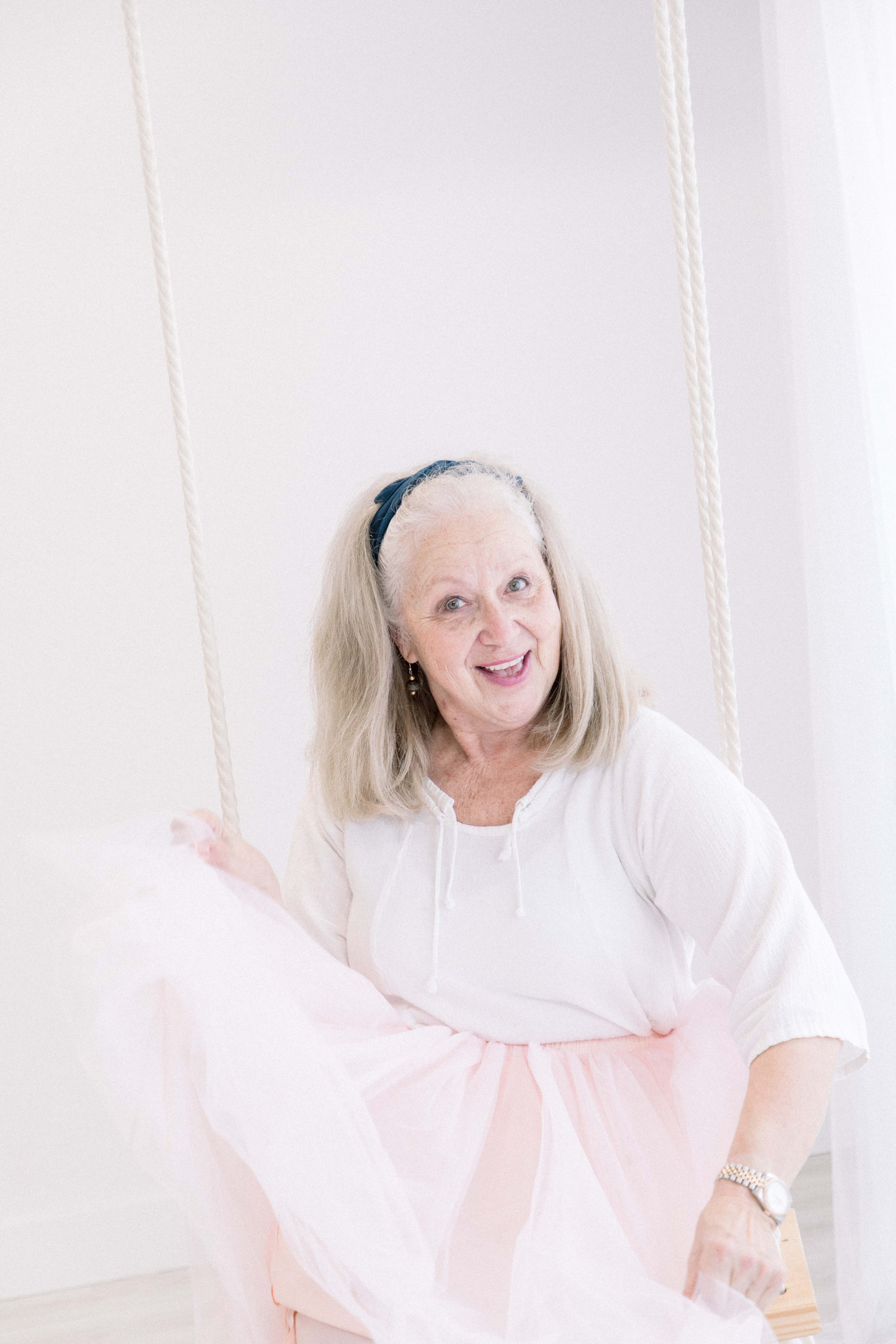 Portrait of woman wearing a tutu sitting on a swing, smiling. Emily VanderBeek Photography, branding photography, portrait photography, Niagara portrait photographer, Niagara branding photographer.