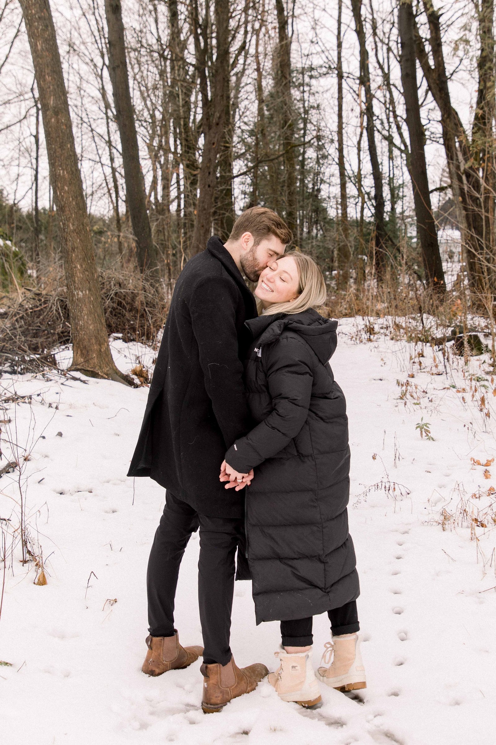 Outdoor Portrait of couple, man giving kiss on woman's cheek. Surprise Proposal. Proposing. Christmas Photos. Ottawa Photographer. Vankleek Hill Photographer. Champlain Photographer. Emily VanderBeek Photography. Candid photography.