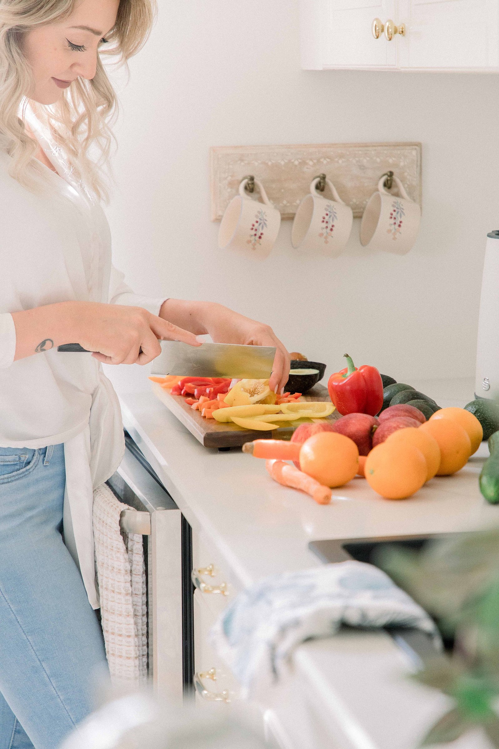 Portrait of a woman chopping fruit in a studio kitchen. Light and airy photography. Emily VanderBeek Photography. Niagara Photographer, Ottawa Photographer, Montreal Photographer.