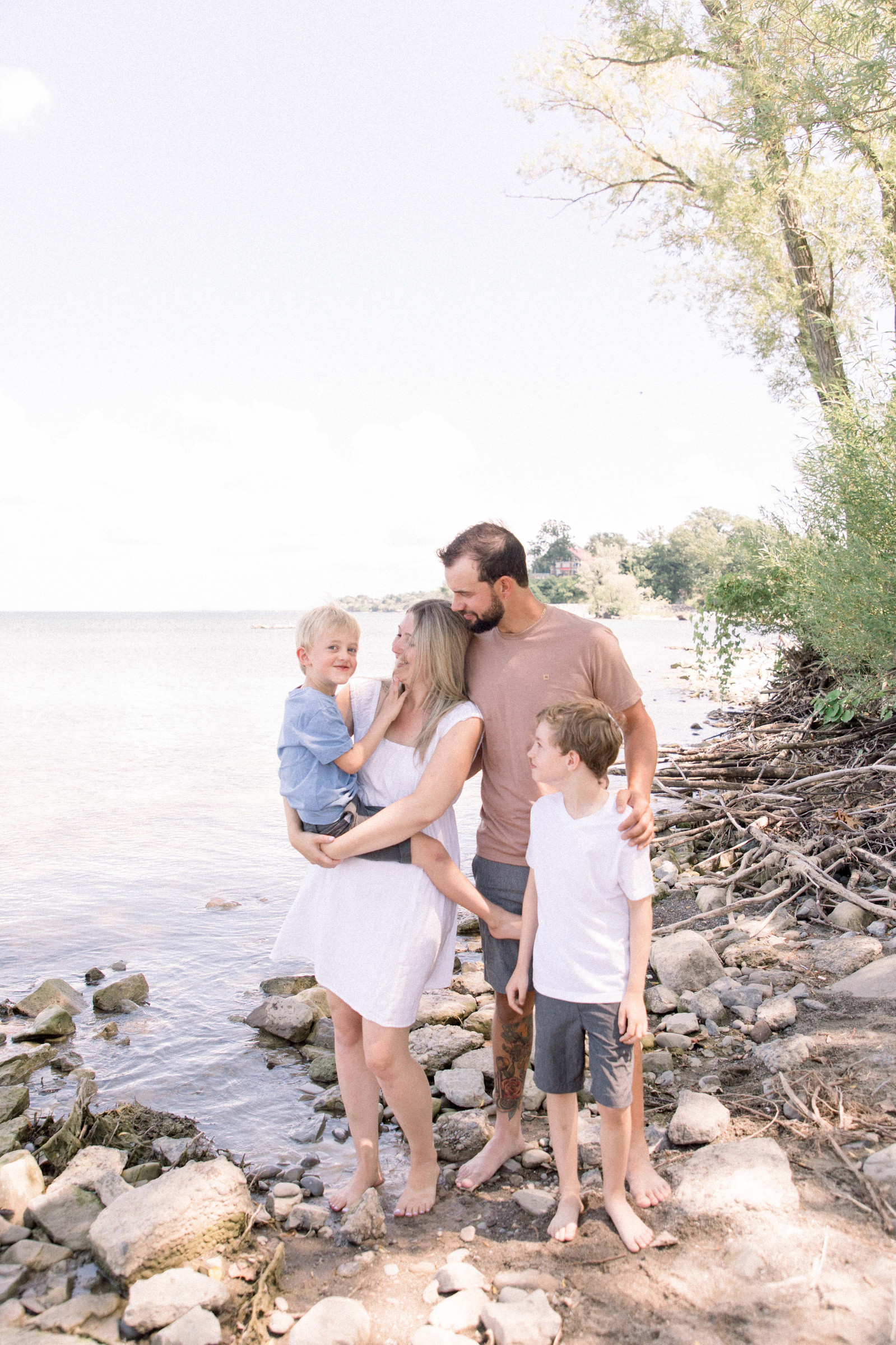 Portrait of family standing together at the beach. Niagara family photographer, Niagara portrait photographer, Niagara motherhood photographer, candid photography, light & airy photography, Emily VanderBeek Photography.