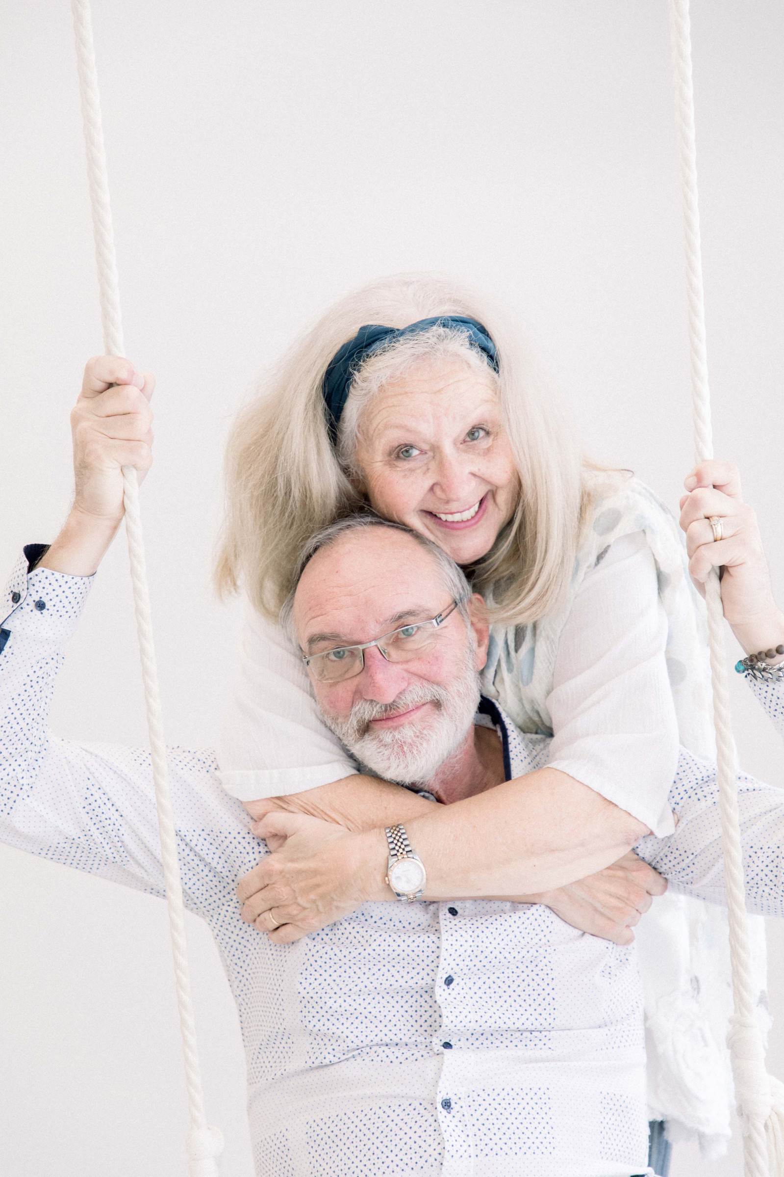 Close up portrait of man and woman hugging each other, while man sits on swing. Emily VanderBeek Photography, branding photography, portrait photography, Niagara portrait photographer, Niagara branding photographer.