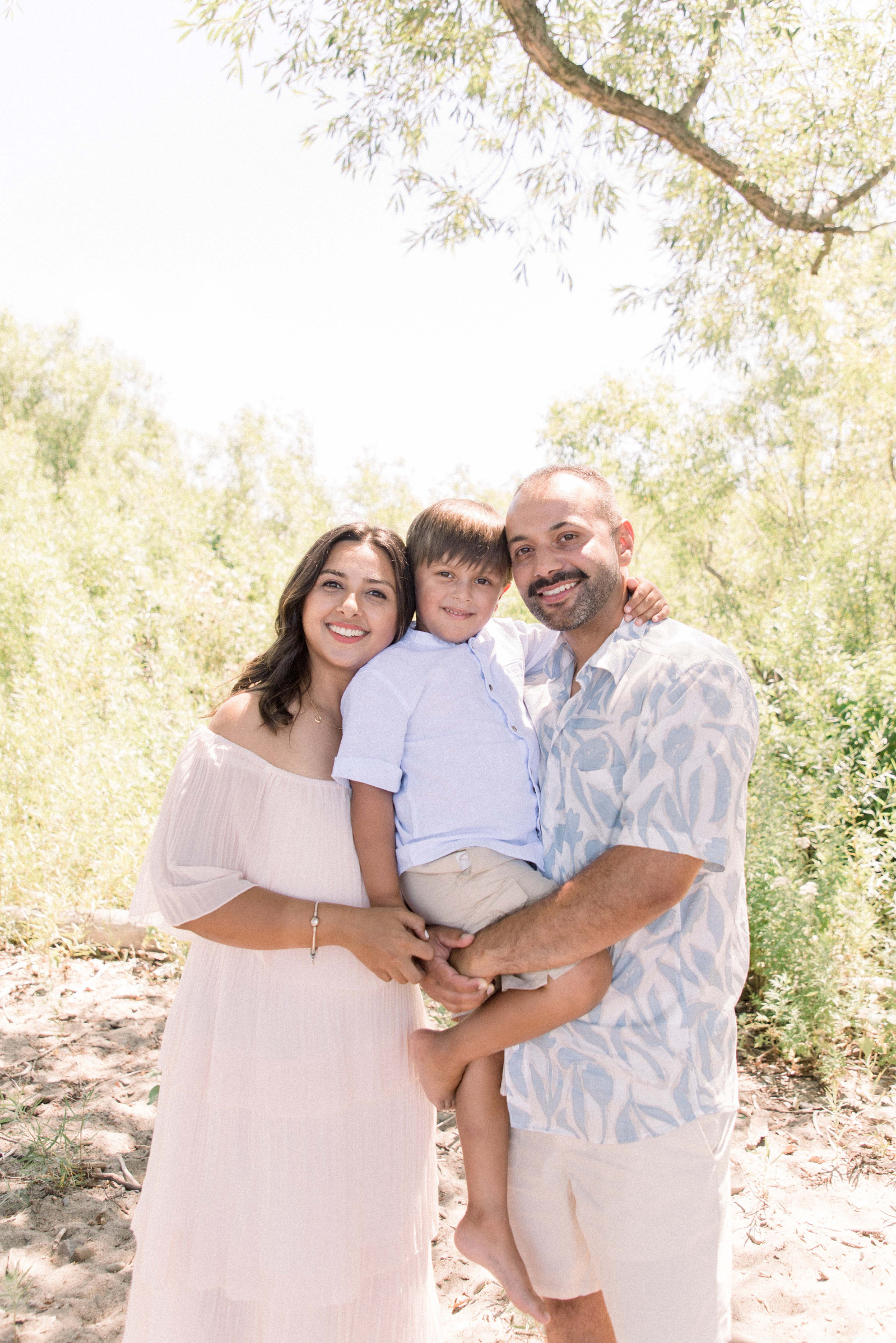 Portrait of family holding their son on the beach. Niagara family photographer, Niagara portrait photographer, Niagara motherhood photographer, candid photography, light & airy photography, Emily VanderBeek Photography.