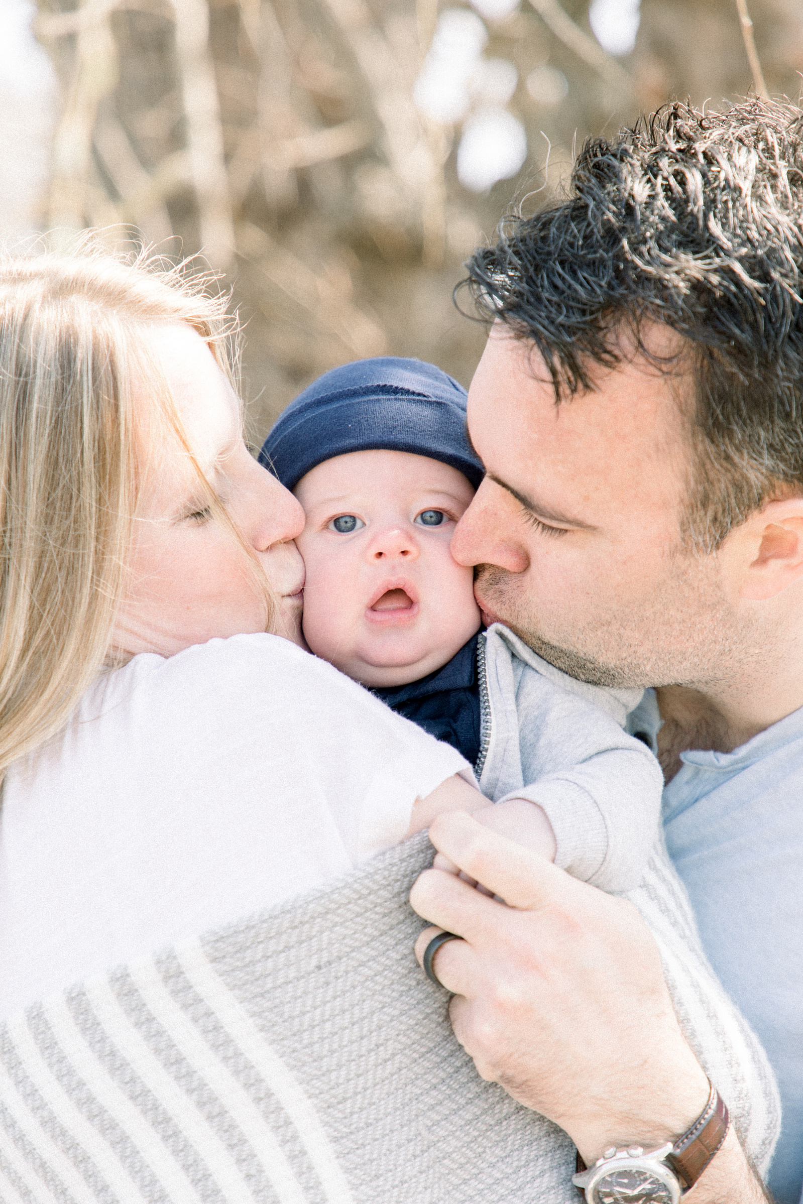 Close up family portrait of parents kissing their baby boy, Niagara portrait photographer, Niagara family photographer, family photography, candid photography.