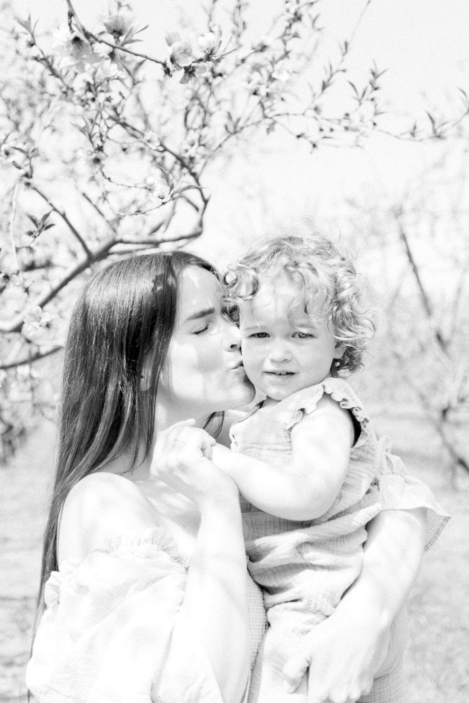 Black and white portrait of mother and baby daughter in an orchard of fruit blossoms. Niagara Family Photographer, Niagara Portrait Photographer, Niagara Motherhood Photographer. Emily VanderBeek Photography, Emily VanderBeek Photo.