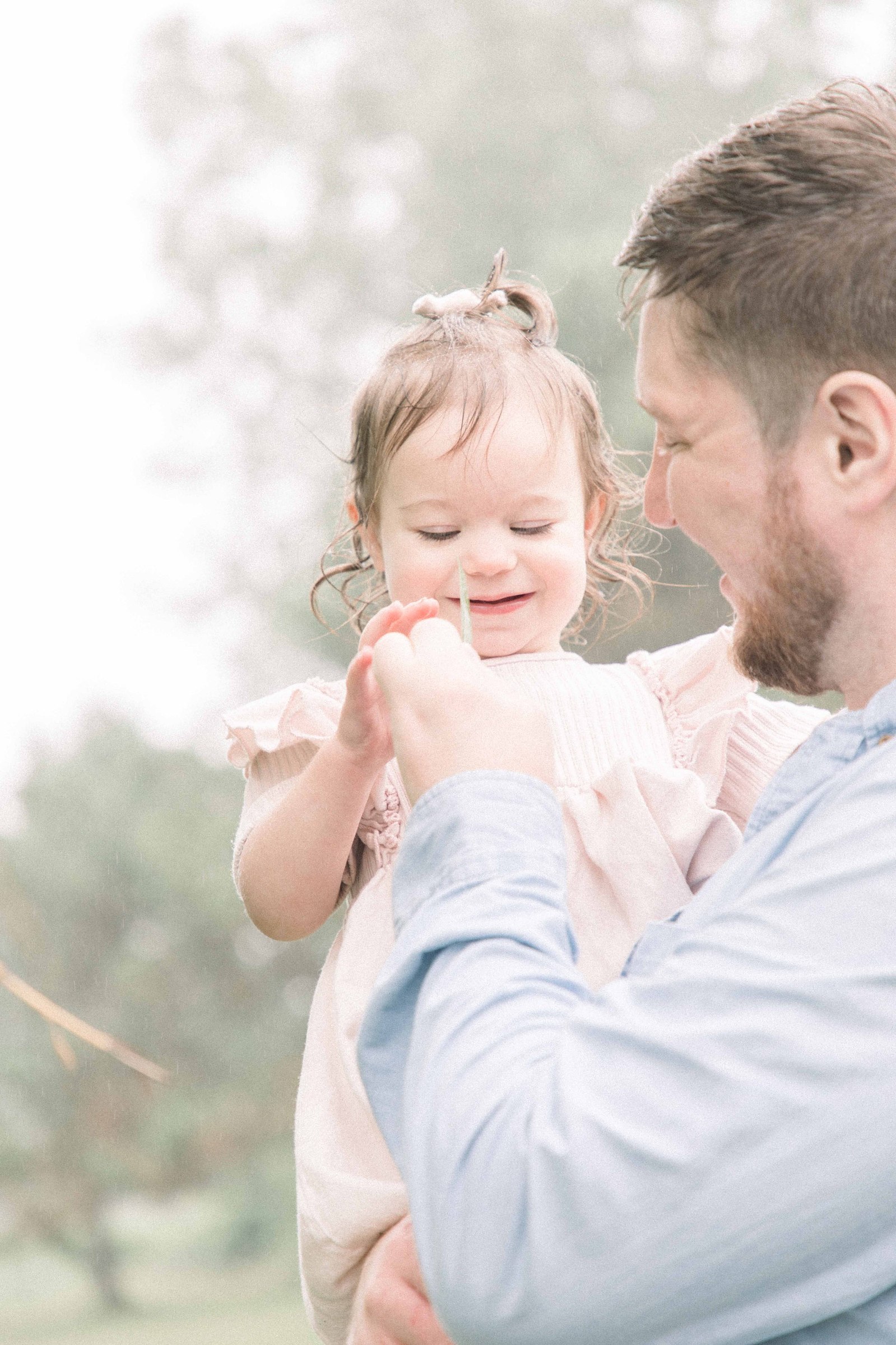 Portrait of father and daughter playing with a leaf and smiling, Niagara Portrait Photographer, Niagara Family Photographer, Niagara Motherhood Photography, Beach Portrait Photography, Emily VanderBeek Photography.