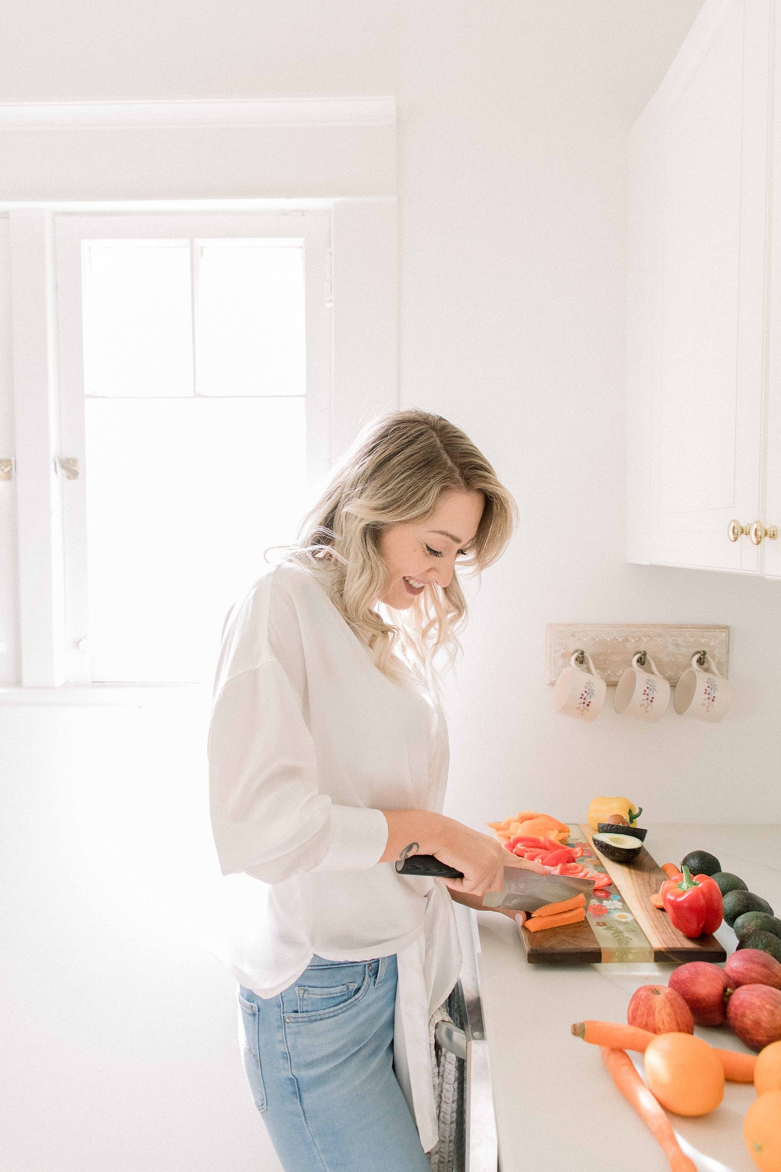 Portrait of a woman chopping fruit in a studio kitchen. Light and airy photography. Emily VanderBeek Photography. Niagara Photographer, Ottawa Photographer, Montreal Photographer.